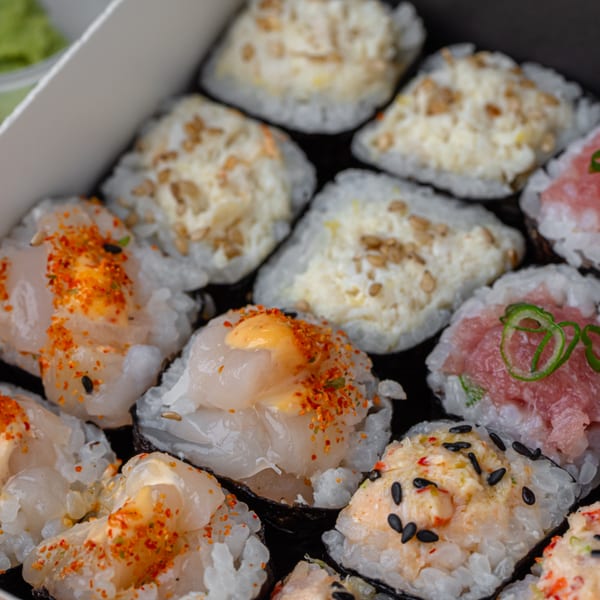 Close-up of Temakase hand rolls with various toppings like scallop, tuna, and creamy sauce.