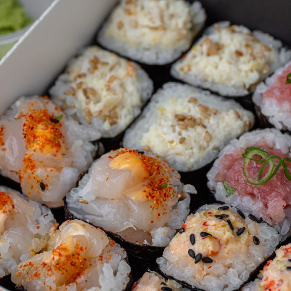 Close-up of Temakase hand rolls with various toppings like scallop, tuna, and creamy sauce.