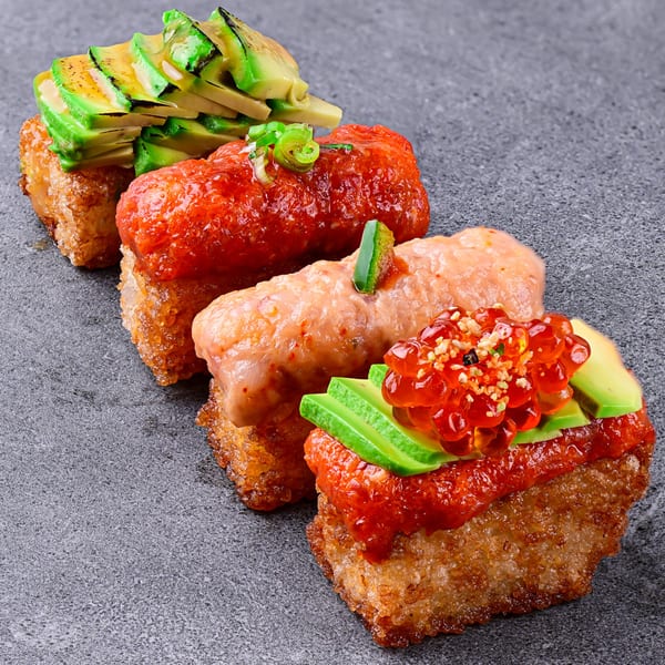 Four Temakase Hand Roll Bar crispy rice sushi pieces with various toppings on a dark surface.